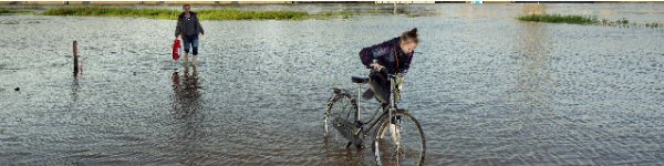 fietser en voetganger lopen door hoog water fietser en voetganger lopen door hoog water