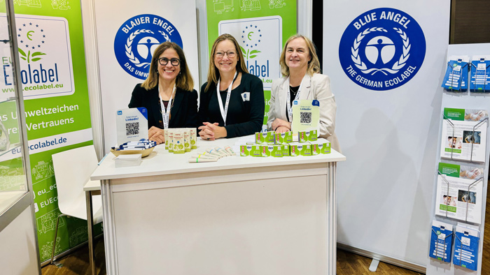 Drei Farauen stehen an einem Stand mit Werbematerial für Ecolabel & Blauer Engel